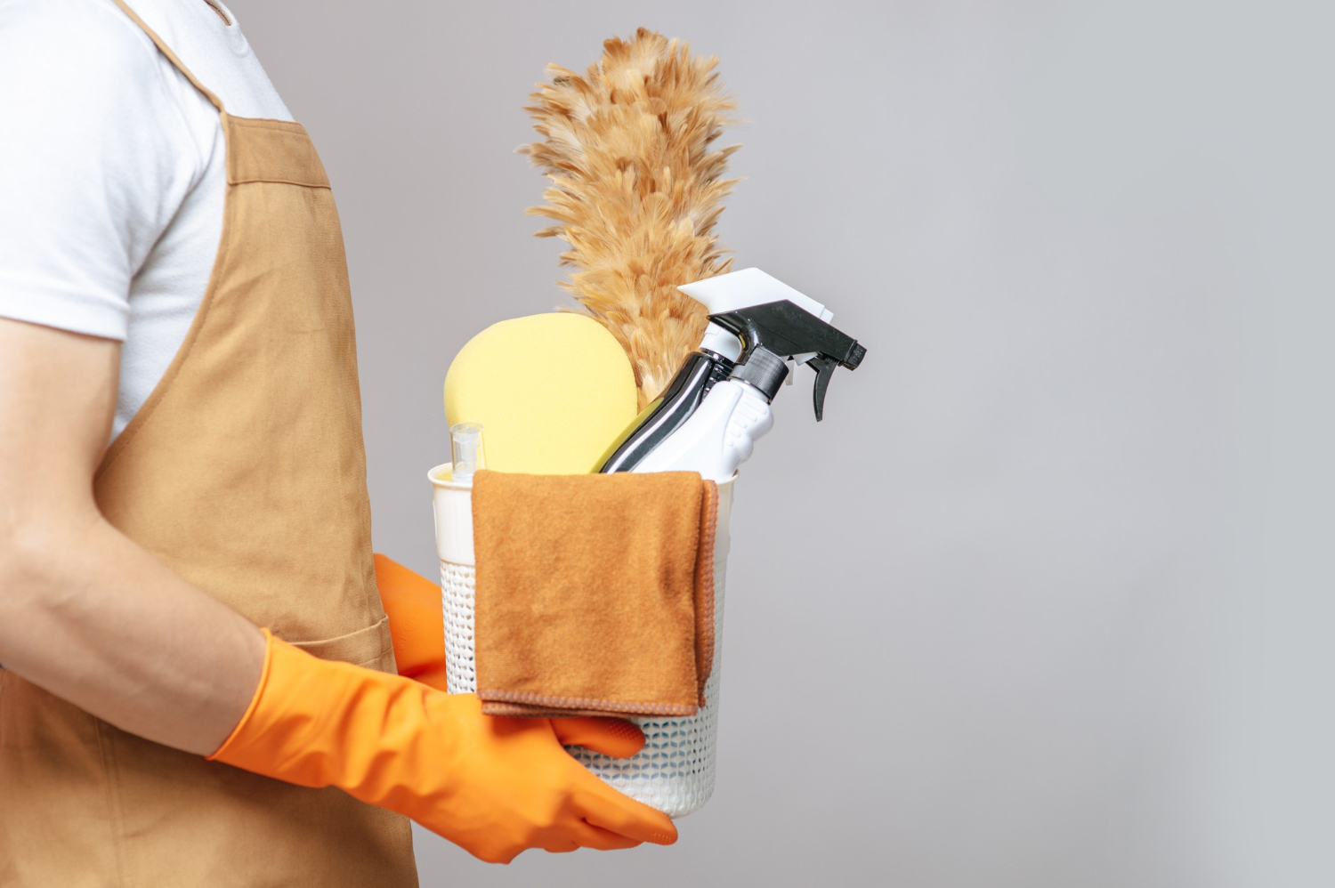 Side View Close Up Hand Young Man Apron Rubber Gloves Holding Basket Cleaning Equipment Feather Duster Spray Bottle Sponge Cloth Wiping Basket