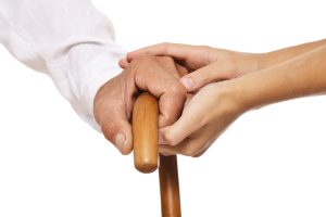 Young,And,Old,Hands,On,Cane,Together,Closeup,Against,White