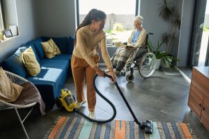 Youthful,Girl,With,Vacuum,Cleaner,Helping,Her,Grandmother,With,Disability