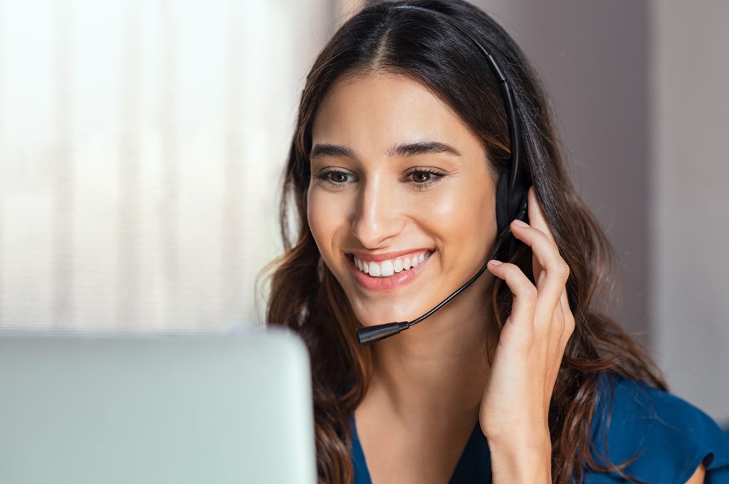 Smiling,Woman,Using,Laptop,While,Talking,To,Customer,On,Phone.