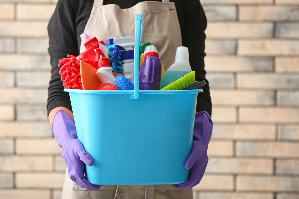Woman,Holding,Bucket,With,Cleaning,Products,And,Tools,Against,Brick